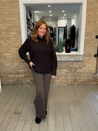 Model wearing a black sweater and grey trousers at Kelly's on Queen